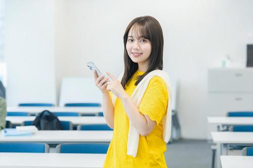教室でスマホを見る女子大学生 スマホ,笑顔,大学生の写真素材