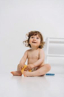笑顔でお座りするオムツの子供 笑顔でお座りするオムツの子供 赤ちゃん,かわいい,お座りの写真素材