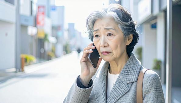 困った表情で電話する高齢者 困った表情で電話する高齢者の写真