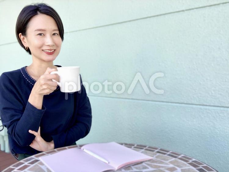 カフェで勉強中にコーヒーを飲む女性 女性,笑顔,インタビューの写真素材