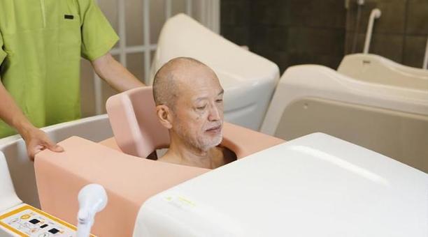 機械浴で入浴介助を受けるアジア人高齢者 機械浴で入浴介助を受けるアジア人高齢者 高齢者,機械浴,入浴の写真素材