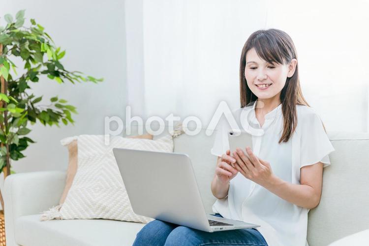 パソコンとスマホを使うミドル世代の女性 スマホ,テレワーク,スマートフォンの写真素材