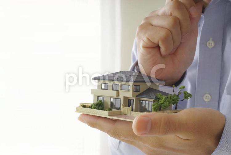 住宅模型を手に考え事をしている男性 不動産,住宅,家の写真素材