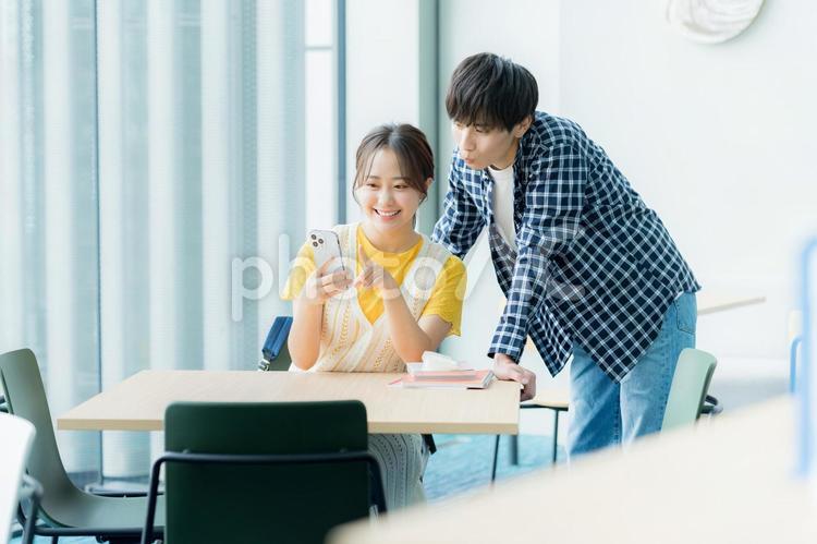 スマホを見ながら話す学生たち スマホ,笑顔,大学生の写真素材