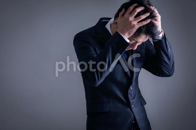 頭を抱えるスーツの男性 悩む,絶望,不安の写真素材