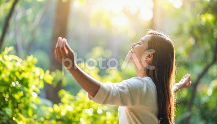 緑の中で伸びをする女性 背伸び,ストレッチ,伸びの写真素材