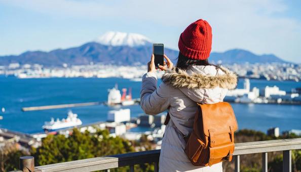 海の向こうを携帯で撮影する観光客の女性 海の向こうを携帯で撮影する観光客の女性の写真