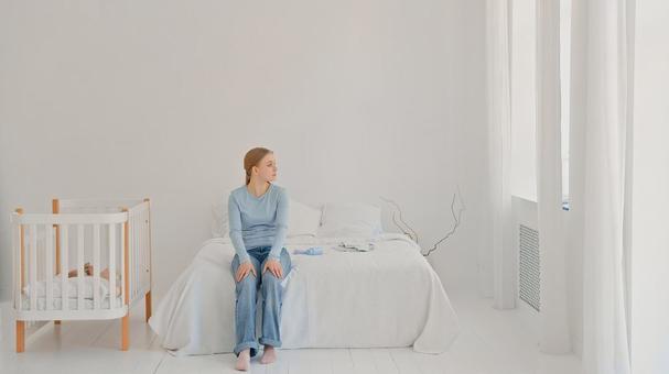 ベッドに座り窓の方を見つめる女性 ベッドに座り窓の方を見つめる女性 女性,育児疲れ,疲れたの写真素材