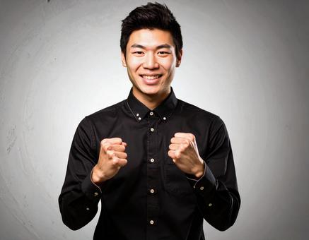 ガッツポーズで喜ぶ若い男性の写真