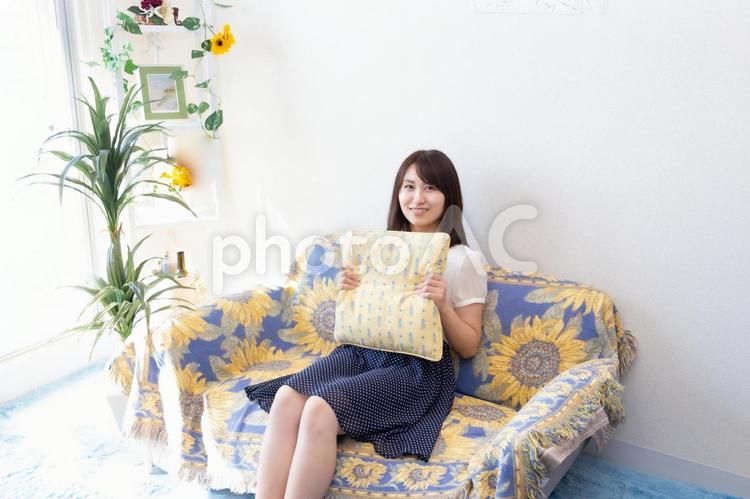 ソファーに座りクッションを抱きかかえている女性 女性,ol,顔の写真素材