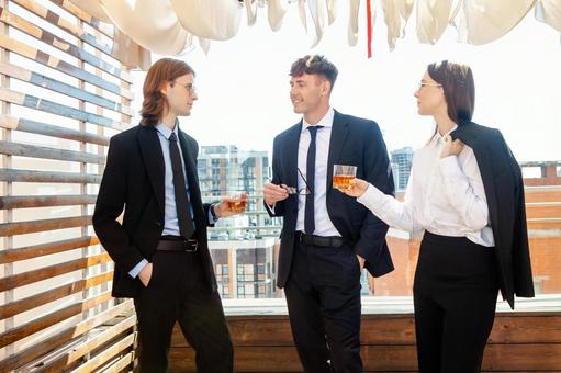 グラスを持ち長髪男性の方を見ている2人の写真