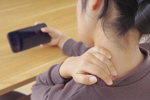 首・肩が痛そうにスマホを操作している女性 スマホ首,ストレートネック,スマホの写真素材