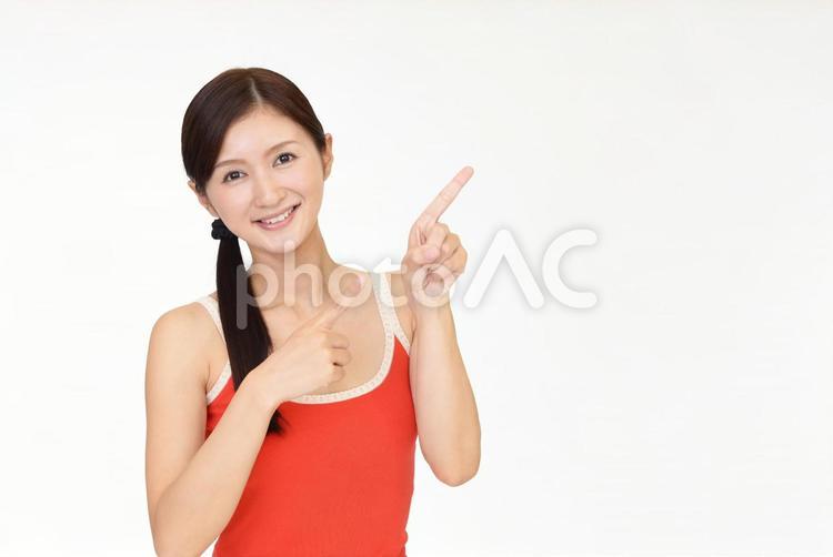 指さすタンクトップ姿の女性 女性,笑顔,タンクトップの写真素材