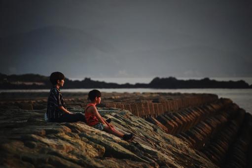 ＜素材＞夕方の防波堤で海を眺める親子 家族,親子,女性の写真素材
