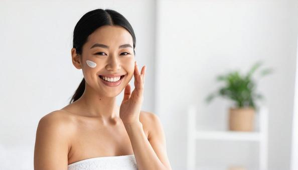 スキンケアをする笑顔の若いアジア人女性の写真