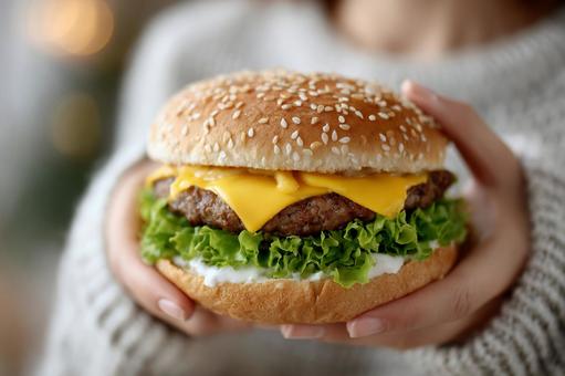 両手で持った大きなチーズバーガー 両手で持った大きなチーズバーガーの写真