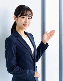 案内ポーズをするスーツ姿の女性 案内ポーズをするスーツ姿の女性の写真