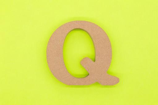 黄緑の背景に置かれた木製の「Q」 アルファベット,q,文字の写真素材