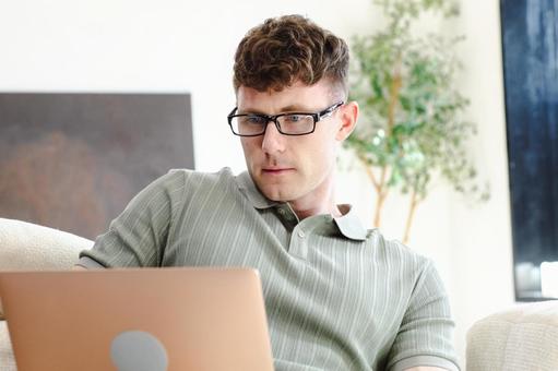 ソファでノートパソコンを使っている男性 男性,外国人,欧米人の写真素材