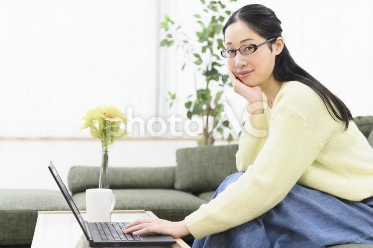 リビングでノートパソコンを操作する女性 ノートパソコン,女性,パソコンの写真素材