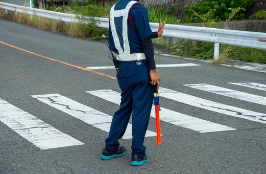 祭り会場の横断歩道で交通整理をする誘導員 祭り会場の横断歩道で交通整理をする誘導員の写真