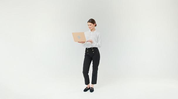 立ちながらパソコンを見ている女性 立ちながらパソコンを見ている女性の写真
