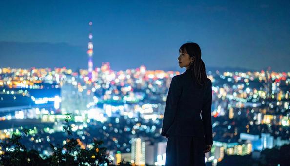 都市の夜景を背景に佇むビジネスマン 都市の夜景を背景に佇むビジネスマンの写真
