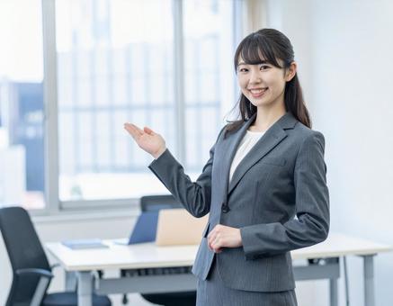 スーツ姿でオフィスを案内する女性 スーツ姿でオフィスを案内する女性の写真