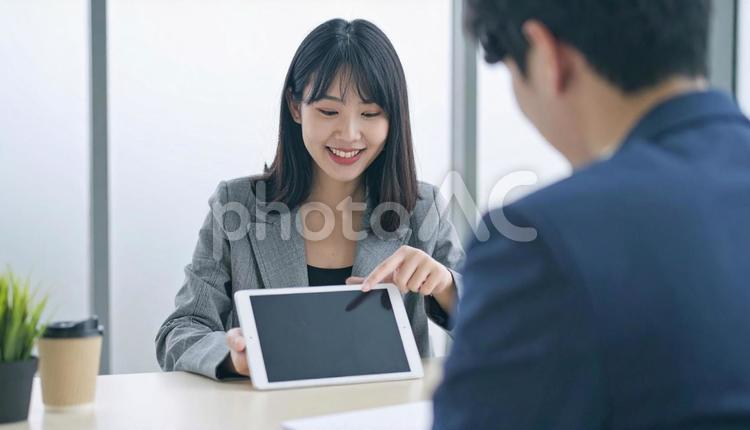 タブレットを使って説明する女性営業マン タブレット,女性営業マン,女性ビジネスマンの写真素材