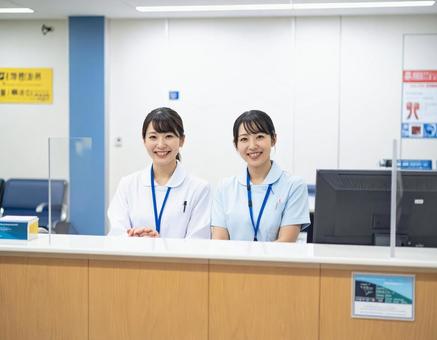 病院の受付コーナーで笑顔で迎える受付嬢 病院の受付コーナーで笑顔で迎える受付嬢の写真