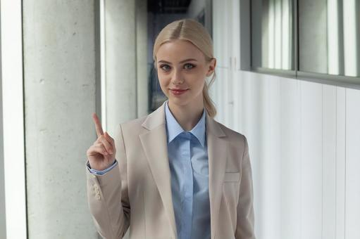 オフィスの通路で人差し指を立てるカメラ目線のビジネスウーマン ビジネスウーマン,ビジネス,女性の写真素材