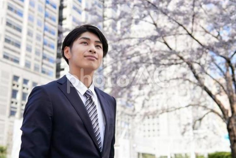 桜を背景に笑顔で立つビジネスマン	 ビジネスマン,男性,新入社員の写真素材