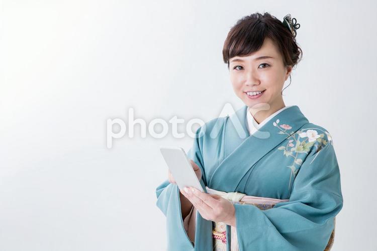 携帯電話を見る着物姿の女性（笑顔） 女性,着物,スマホの写真素材