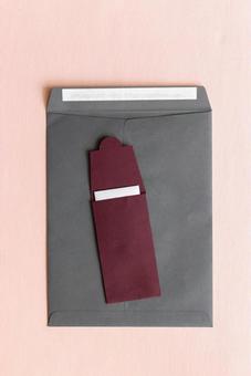 黒い角形封筒とカードの入った茶色い縦長の洋形封筒(ピンク背景) 黒い角形封筒とカードの入った茶色い縦長の洋形封筒(ピンク背景) モックアップ,物撮り,封筒の写真素材
