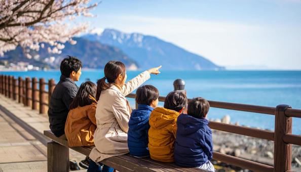 海辺の堤防に座る親子 海辺の堤防に座る親子の写真