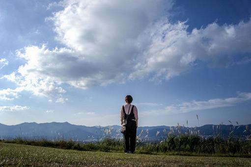 ＜素材＞山頂から広がる街並みを眺める女性の写真