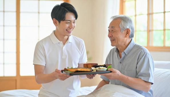 高齢男性と男性介護士の穏やかな食事風景 高齢男性と男性介護士の穏やかな食事風景の写真