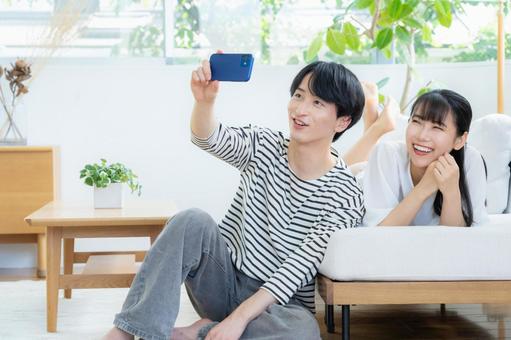 リビングでスマホを見る若いカップル リビングでスマホを見る若いカップル 夫婦,カップル,リビングの写真素材