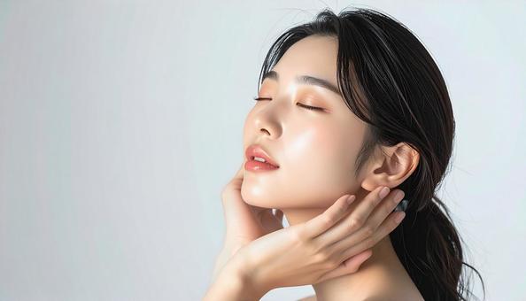 頬に両手を当てて目を瞑る透明感のある女性の写真