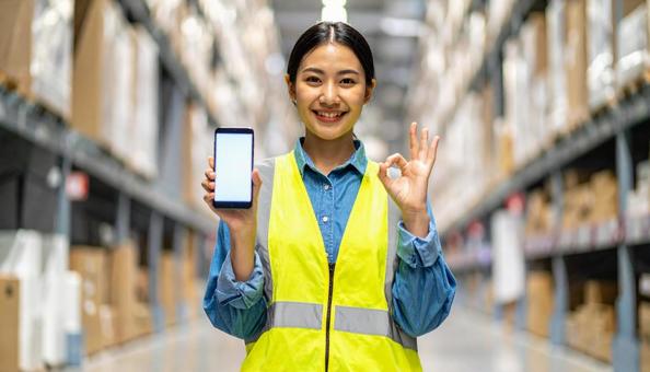 スマホを持ちOKサインの日本人女性作業員 スマホを持ちOKサインの日本人女性作業員の写真