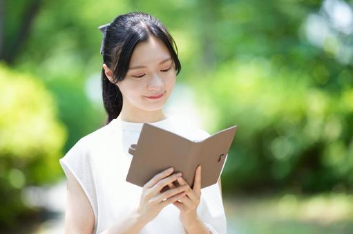 白いノースリーブワンピースの女性が本を見つめるの写真