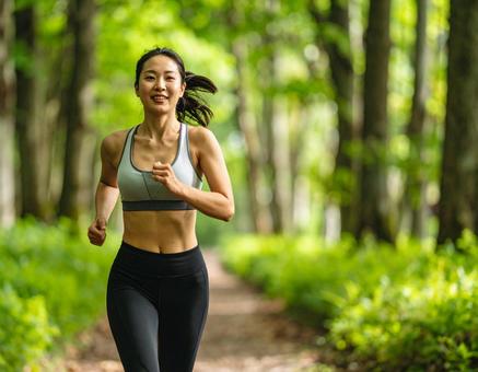 公園でジョギングをする若い女性 公園でジョギングをする若い女性の写真