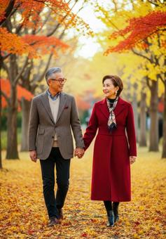 手をつなぎ紅葉道を散策するシニアカップル 手をつなぎ紅葉道を散策するシニアカップルの写真