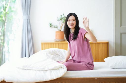 カメラ目線で手をあげる笑顔の女性 女性,手をあげる,ポーズの写真素材