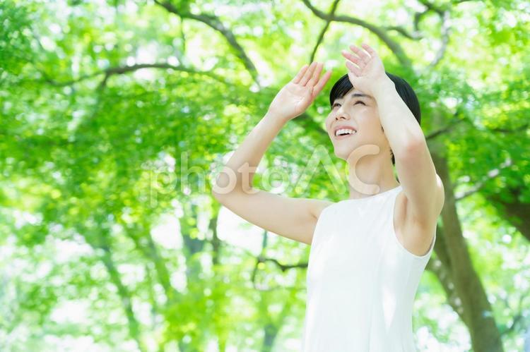 緑の中でスキンケアをする若い女性 スキンケア,ビューティー,女性の写真素材