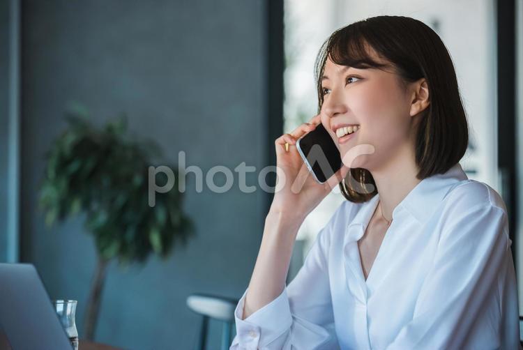 スマホで通話をする笑顔のビジネスウーマン 女性,ビジネス,ビジネスウーマンの写真素材