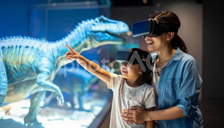 VRゴーグルで恐竜のホログラムを見る親子 vr,仮想現実,ホログラムの写真素材