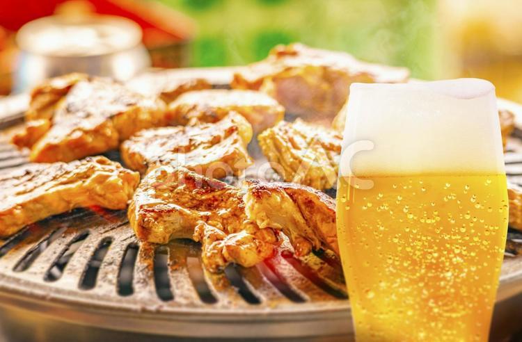 焼肉の背景と泡が垂れた水滴のついたグラスビールの画像 ビール,夏,バーベキューの写真素材