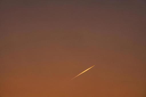 夕焼けに染まる空を飛んでいく飛行機雲 夕焼け,夕暮れ,夕方の写真素材