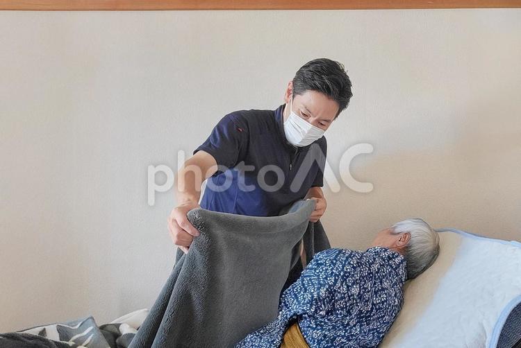 布団をかける訪問介護士の男性 介護福祉士,福祉,介護士の写真素材